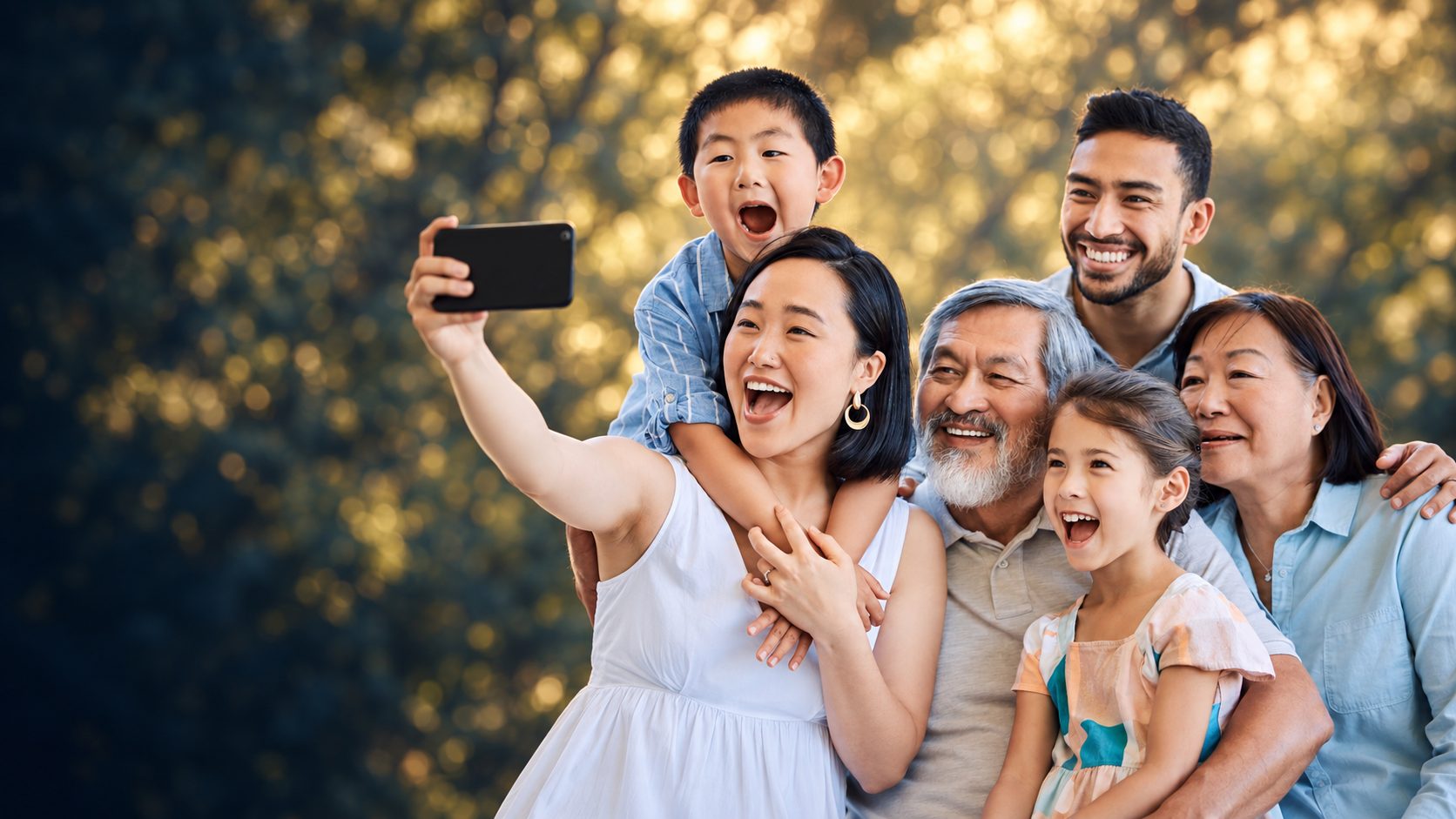 Three generations of a smiling family together outdoors, taking a photo